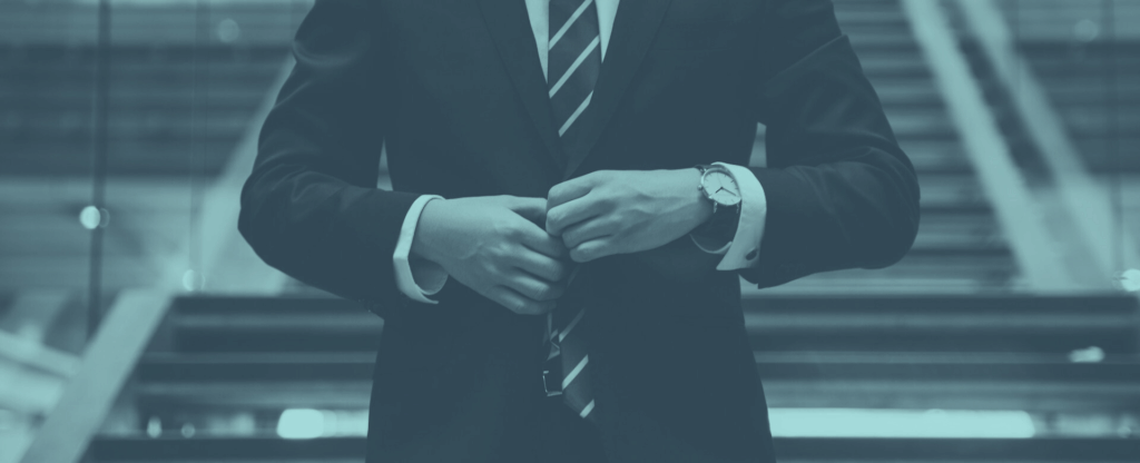 Professioneller Geschäftsführer im blauen Anzug passt seine Armbanduhr an, Symbol für präzises Zeitmanagement und steuerliche Optimierung von Führungskräften.