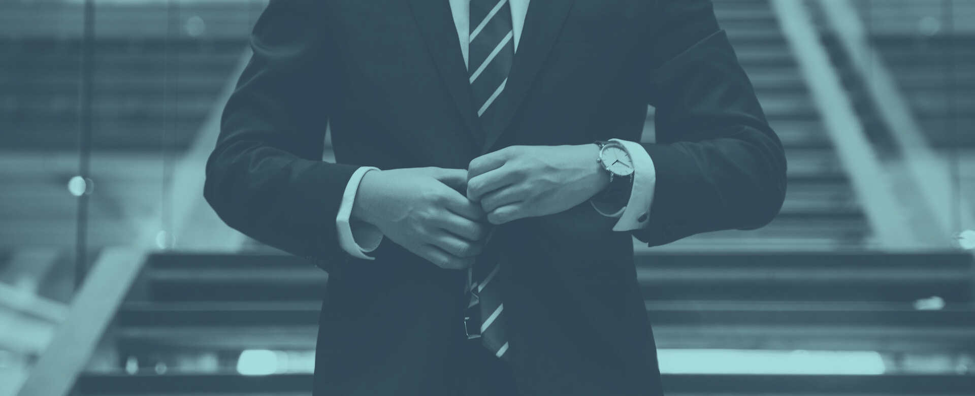 Professioneller Geschäftsführer im blauen Anzug passt seine Armbanduhr an, Symbol für präzises Zeitmanagement und steuerliche Optimierung von Führungskräften.