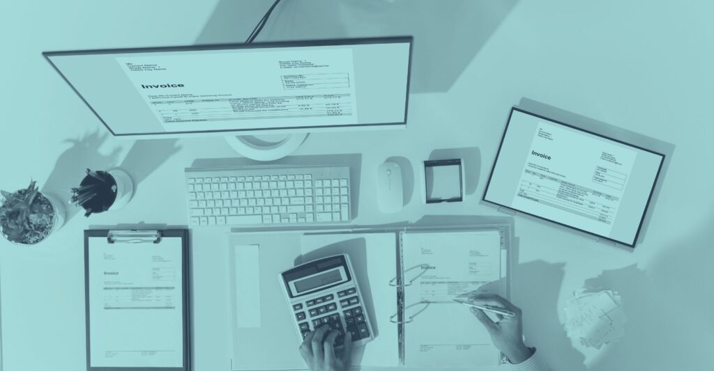 Stapel bunter Steuerdokumente und Investitionspläne mit Laptop und Brille auf Schreibtisch – symbolisiert Steuertipps und steueroptimierte Investitionen für Unternehmen in Österreich 2025