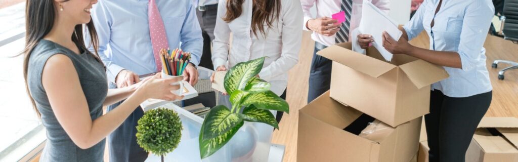 Büroangestellte verpacken Arbeitsmaterialien in Kartons für den Umzug – symbolisiert die Büroübersiedlung oder Firmenumzug in Österreich.
