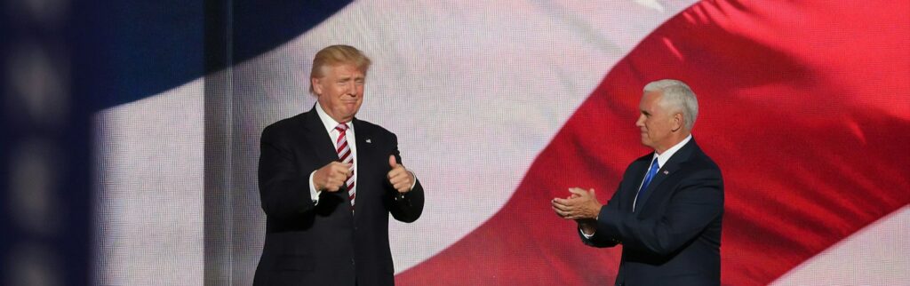 Donald Trump auf Bühne vor amerikanischer Flagge – symbolisiert die Auswirkungen des Big Beautiful Bill auf Österreichs Wirtschaft und Steuersystem.