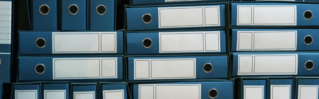 "Gestapelte blaue Aktenordner symbolisieren die Reduzierung von Bürokratie und administrative Vereinfachung für Bauunternehmen in Österreich durch neue Entbürokratisierungsmaßnahmen 2025