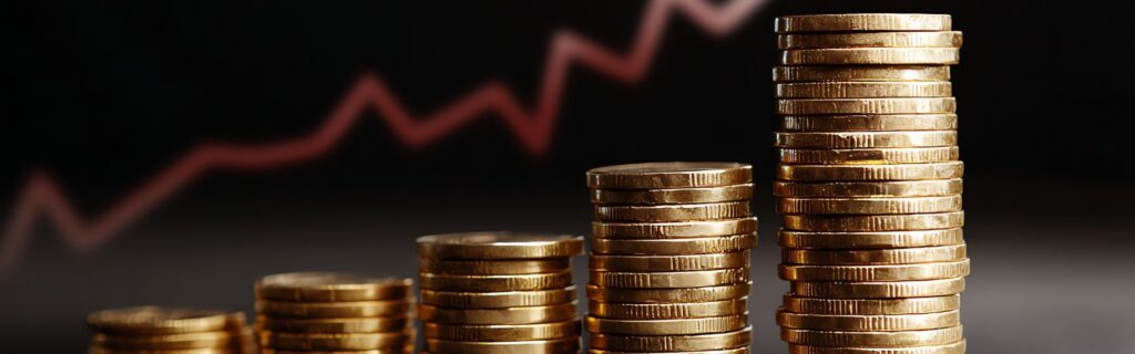 Aufgestapelte Goldmünzen vor Finanzgraph – symbolisiert die Kombination verschiedener Zuschüsse und Förderungen für Bauunternehmen im Rahmen der neuen Standort-Förderung 2025. Visualisiert finanzielle Vorteile und Wachstumsmöglichkeiten durch optimale Förder-Stacks.