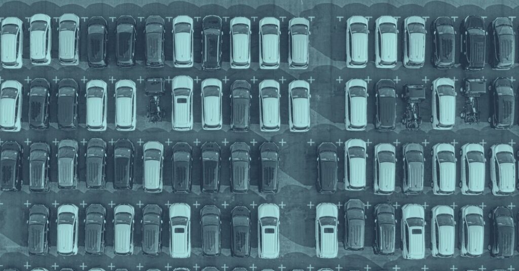 Luftaufnahme eines großen Firmenwagen-Parkplatzes mit über 80 Fahrzeugen, ordentlich in Reihen geparkt. Die strukturierte Anordnung symbolisiert die Komplexität der Sachbezugsberechnung bei mehreren Firmenwagen und die Bedeutung von Fahrzeugpool-Dokumentation gemäß BFG-Urteil November 2025 in Österreich. Das Bild dient als visueller Einstieg in das Thema doppelte Sachbezug und Mehrfachansatz für Arbeitgeber.