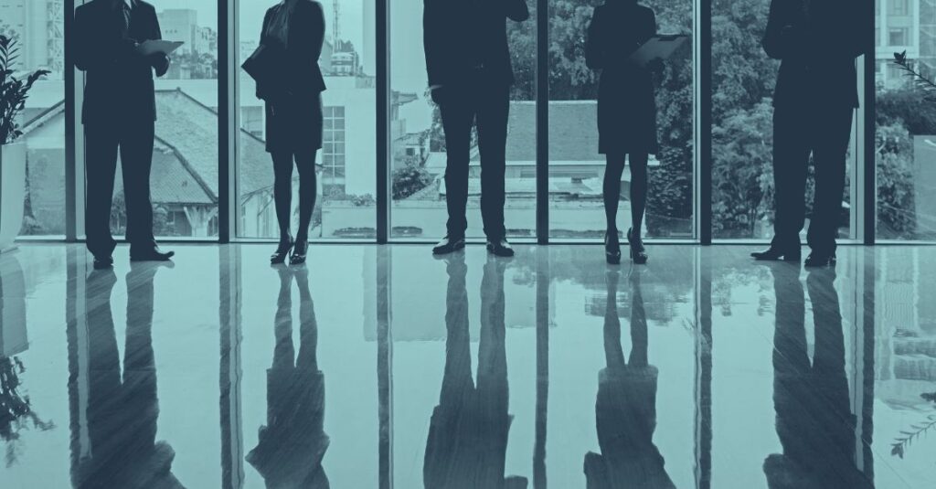 Gruppe von Unternehmern im Büro vor Panoramafenstern als Symbol für Checkliste zum Jahresende für Unternehmen﻿.