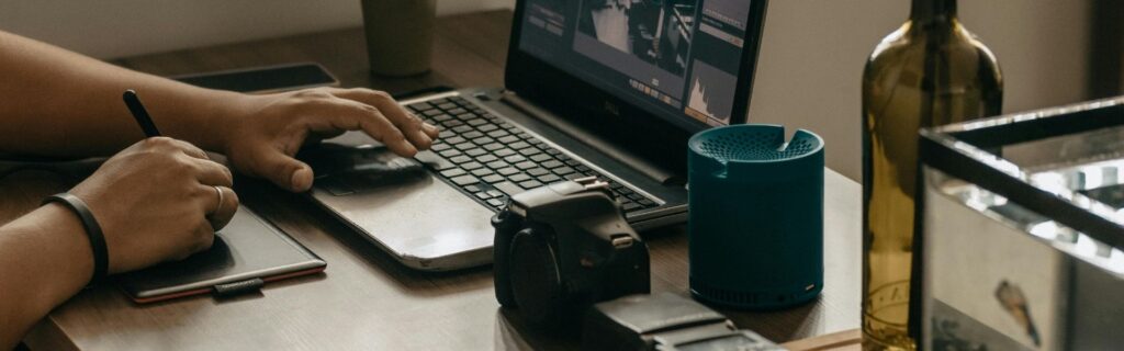 Selbständiger Fotograf am Schreibtisch mit Laptop, Grafiktablet, Stift und Kamera: Zeigt kreative Berufe und digitale Dienstleister die von der Basispauschalierung 2026 in Österreich profitieren können durch vereinfachte Gewinnermittlung
