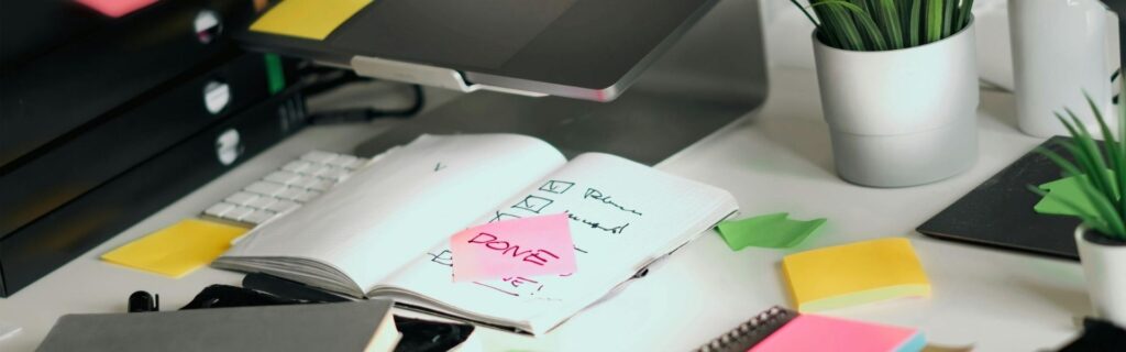 Aufgeklapptes Notizbuch mit bunten Post-it-Notizen und Checkliste auf Schreibtisch – Übersicht zur optimalen steuerlichen Absetzung von Homeoffice-Kosten für Selbständige in Österreich 2026