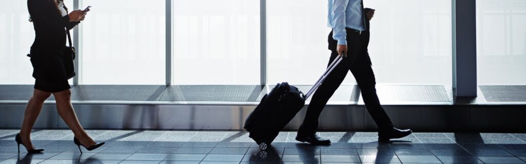 Geschäftsreisende mit Koffern im Flughafen – Illustration zu aktuellen Reisekosten-Pauschalen, Taggeld und Kilometergeld für Dienstreisen in Österreich.