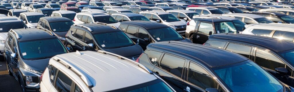 Großer Parkplatz mit zahlreichen abgestellten Firmenwagen, symbolisch für Poolfahrzeuge und die steuerliche Behandlung von Fahrzeugflotten im Unternehmen